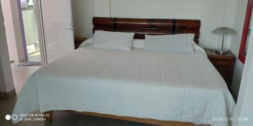 a bedroom with a large white bed with a wooden headboard at Hotel Villas del Rey in Chachalacas