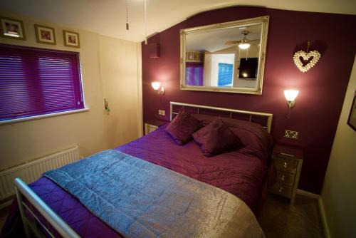 a bedroom with a bed with purple sheets and a mirror at Luxurious Rural Cabin with Hot Tub in West Chiltington