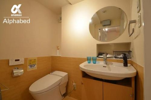 een badkamer met een toilet, een wastafel en een spiegel bij Alphabed TakamatsuKawaramachi WEST 701 / Vacation STAY 21586 in Takamatsu