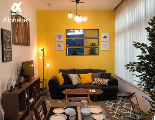 a living room with a black couch and a yellow wall at Alphabed TakamatsuHyogomachi 602 / Vacation STAY 21871 in Takamatsu