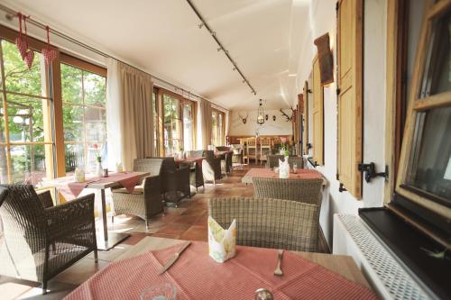a restaurant with tables and chairs and windows at Hotel Daimerwirt in Moosinning