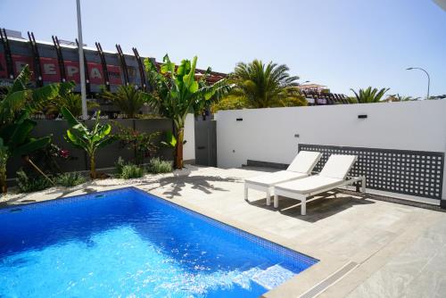 a patio with a blue swimming pool next to a white building at Luxury Villa in Los Cristianos in Arona