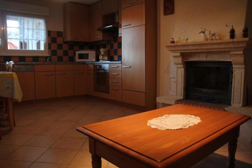 une cuisine avec une table en bois et une cheminée dans l'établissement Gîte Bretz, à Wasserbourg