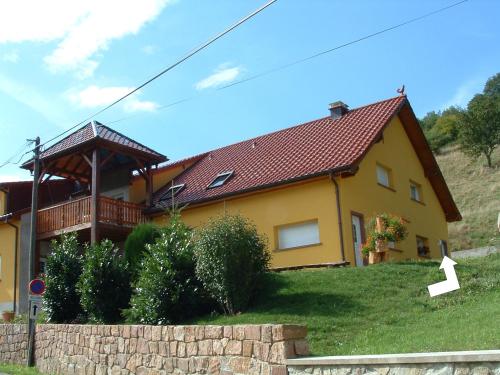 une maison jaune avec un toit rouge sur une colline dans l'établissement Gîte Bretz, à Wasserbourg