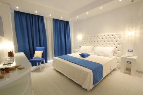 a bedroom with a large bed and a blue chair at Ludwig Boutique Hotel & Spa in Bolsena