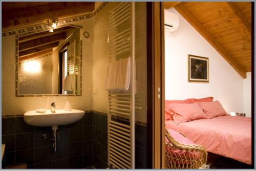 ein Bad mit einem Waschbecken, einem Bett und einem Spiegel in der Unterkunft B&B Corte Alfier in Mortegliano