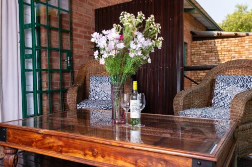 a glass table with a vase of flowers on a patio at Olive Tree Farm in Magaliesburg