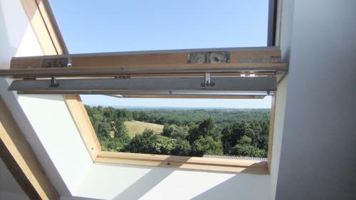 an open window with a view of a forest at Chambres d'Hôtes Le Foursou in Le Bouyssou