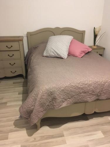a bedroom with a bed with a pink pillow and a dresser at Villa le Tresquel in Mostuéjouls