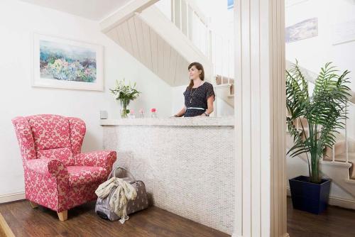 a woman standing behind a counter in a room with a chair at The Strand Inn in Dunmore East