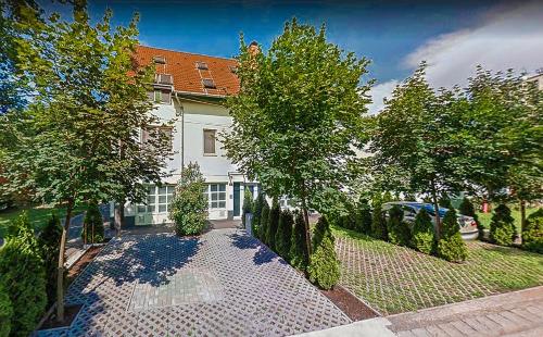 une maison avec une clôture et des arbres devant elle dans l'établissement Nexus Vendégház Szeged, à Szeged