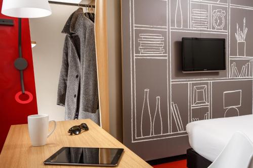 a room with a table and a tv on a wall at ibis Glasgow City Centre – Sauchiehall St in Glasgow