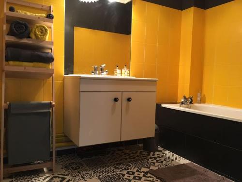 uma casa de banho com paredes amarelas, um lavatório e uma banheira. em Cosy Flat Cherbourg em Cherbourg en Cotentin