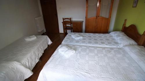 two beds in a bedroom with white sheets at Pensión Sandoval by gaiarooms in León