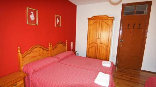 a bedroom with a bed with a red wall at Pensión Sandoval by gaiarooms in León