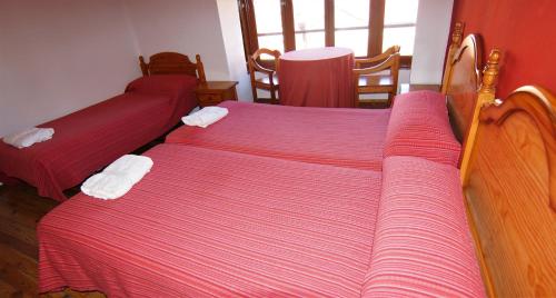 two beds in a room with red and white sheets at Pensión Sandoval by gaiarooms in León