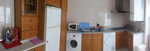 a kitchen with a white refrigerator and a washing machine at Pensión Sandoval by gaiarooms in León
