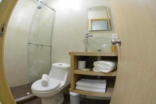 a bathroom with a toilet and a glass shower at La Hermosa Hotel in Buga