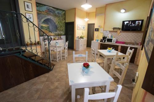 a room with tables and chairs and a kitchen at B&B Sa Lumenaria "da Raimonda" in Sorgono