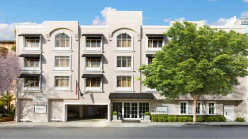 a white building with a tree in front of it at Mosaic Hotel Beverly Hills in Los Angeles