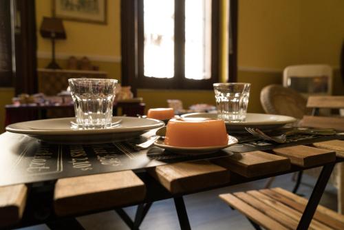 een houten tafel met twee borden en glazen erop bij Inn Liberty in Giarre