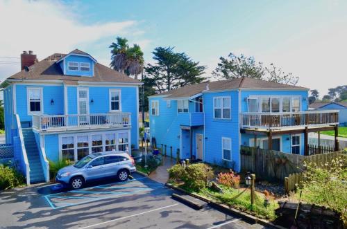 a blue house with a car parked in a parking lot at Captain's Inn at Moss Landing in Moss Landing