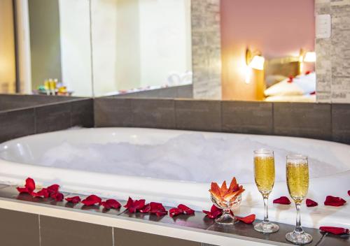 a bath tub with two glasses of champagne and roses at Hostal Oro Orense in Quito