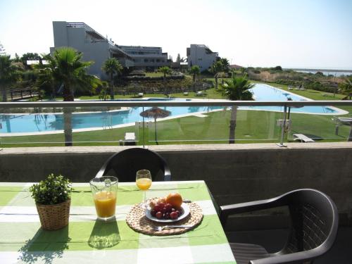 a table with a bowl of fruit and two glasses of orange juice at Life Apartments El Rompido in El Rompido