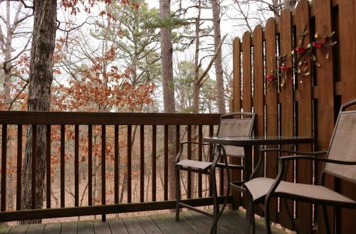 a deck with two chairs and a table and a fence at The Grand Treehouse Resort in Eureka Springs