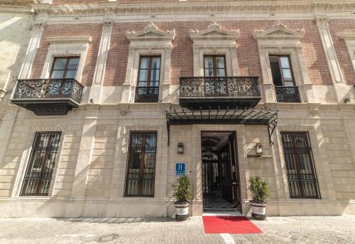 a large brick building with balconies and a door at Hotel Casa Palacio María Luisa in Jerez de la Frontera