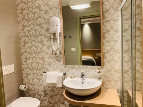 a bathroom with a sink and a mirror and a toilet at Hotel Liane Riccione in Riccione