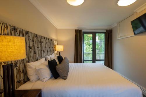 a bedroom with a large white bed with pillows at Peppers Beacon in Queenstown
