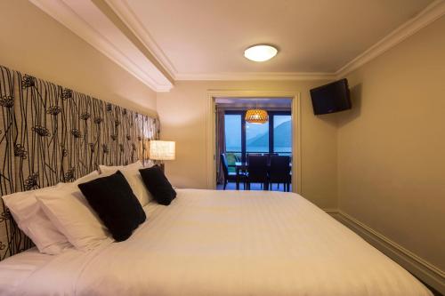 a bedroom with a large white bed with black pillows at Peppers Beacon in Queenstown