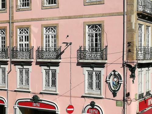 a pink building with balconies and a clock on it at Clérigos Ville Porto Rooms in Porto