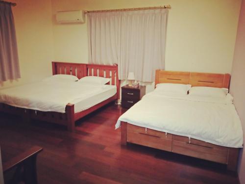 two beds in a room with wooden floors at manor in Houli