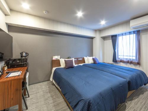 um quarto com uma cama azul e uma secretária em HOTEL LiVEMAX Sapporo Susukino em Sapporo