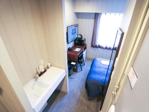 a bathroom with a sink and a desk with a computer at HOTEL LiVEMAX Sapporo Susukino in Sapporo