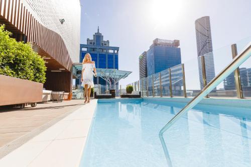 a woman walking next to a swimming pool on a building at Mercure Brisbane King George Square in Brisbane