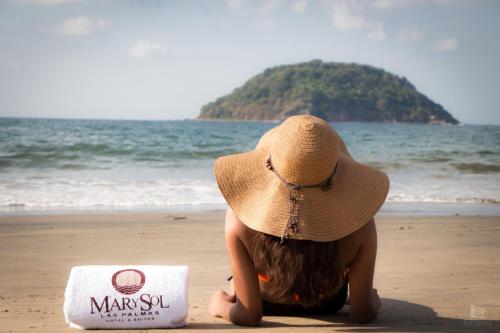 a woman in a straw hat sitting on the beach at MarySol Las Palmas in Rincon de Guayabitos