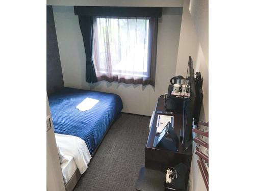 um pequeno quarto com uma cama e uma janela em HOTEL LiVEMAX Okayama em Okayama