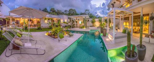 a house with a swimming pool with chairs and an umbrella at Umami Hotel - Adults Only in Puerto Viejo