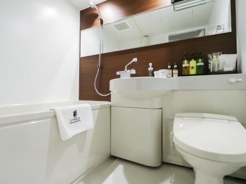 HOTEL LiVEMAX Tokyo Shintomicho في طوكيو: حمام به مرحاض أبيض ومغسلة