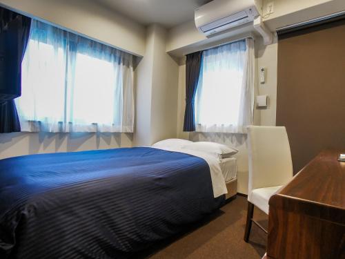 大阪的住宿－HOTEL LiVEMAX Umeda Doyama，一间卧室配有一张床、一张书桌和两个窗户。