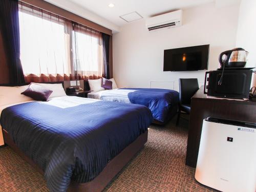 a hotel room with two beds and a flat screen tv at HOTEL LiVEMAX Osaka Dome Mae Hotel in Osaka