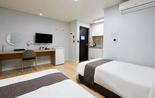 a bedroom with two beds and a desk and a television at Malu Hotel Suwon in Suwon