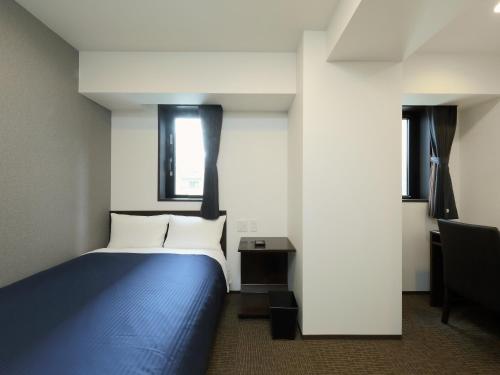 a bedroom with a blue bed and a window at HOTEL LiVEMAX Meieki in Nagoya