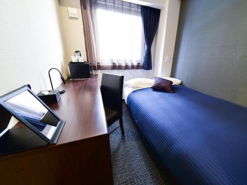 ein Hotelzimmer mit einem Schreibtisch, einem Bett und einem Computer in der Unterkunft HOTEL LiVEMAX Toyosu-Ekimae in Tokio