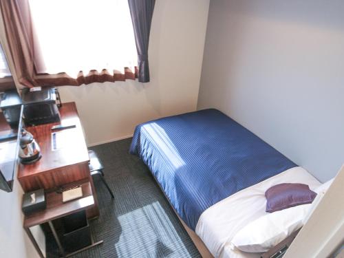 a small bedroom with a bed and a desk at HOTEL LiVEMAX Tokyo Ayase-Ekimae in Tokyo
