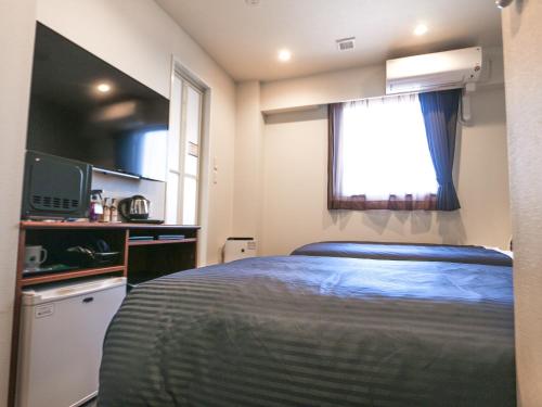 a small bedroom with a bed and a window at HOTEL LiVEMAX Tokyo Ayase-Ekimae in Tokyo