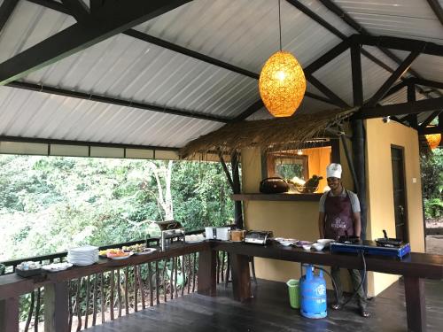 a man standing in a kitchen with a table at Sinharaja Forest Edge in Deniyaya